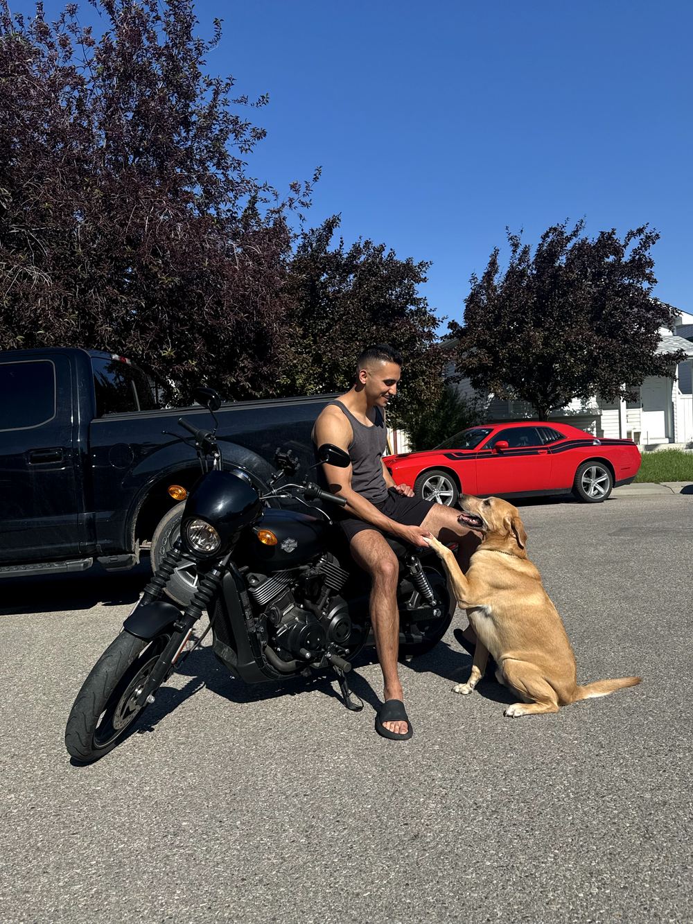 Abhi and his dog shaking paws beside his motorcycle
