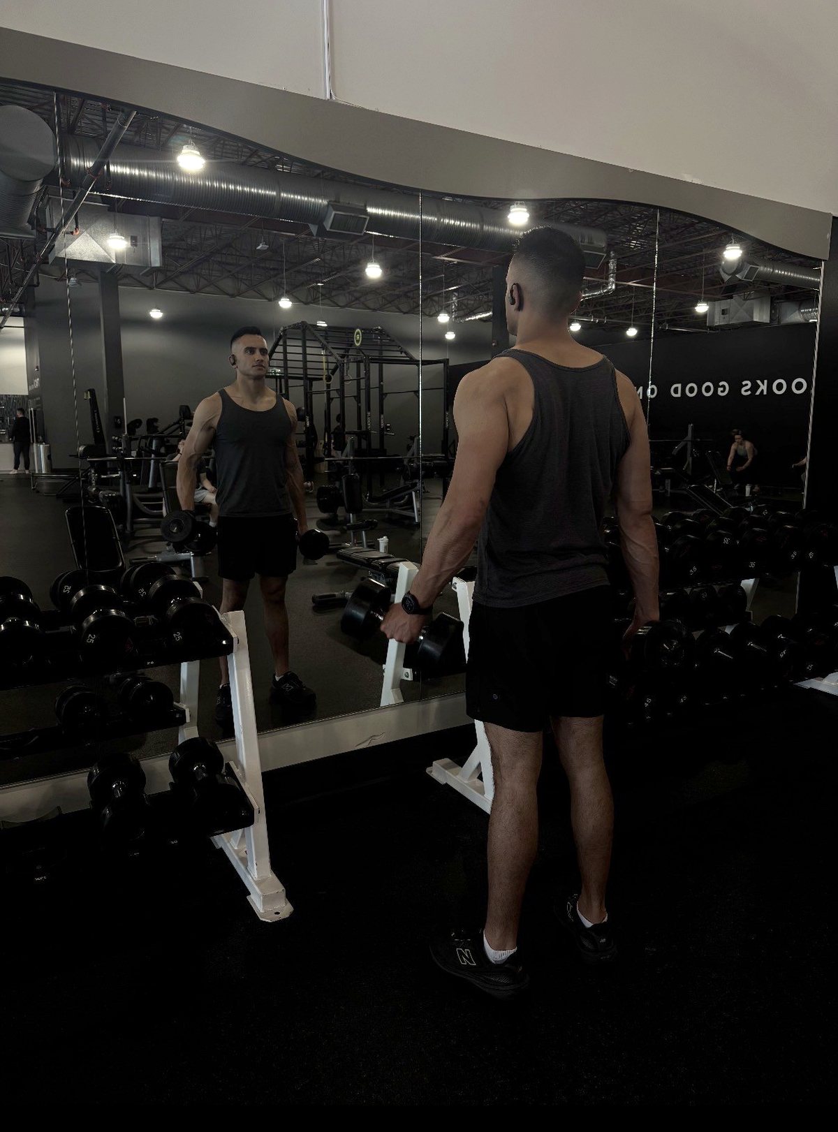 Abhi Mittu training dumbbells at the gym mirror